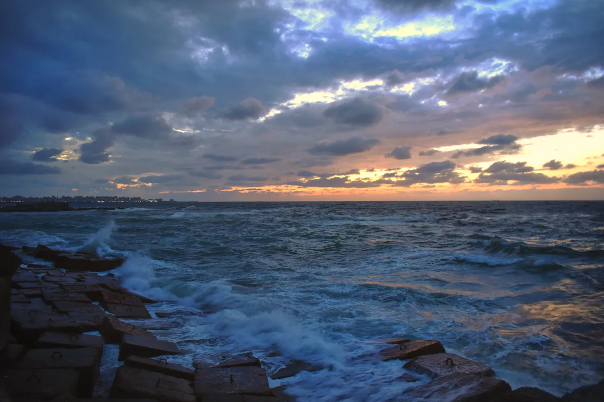Mediterranean waves beneath a dramatic sunset sky in Alexandria