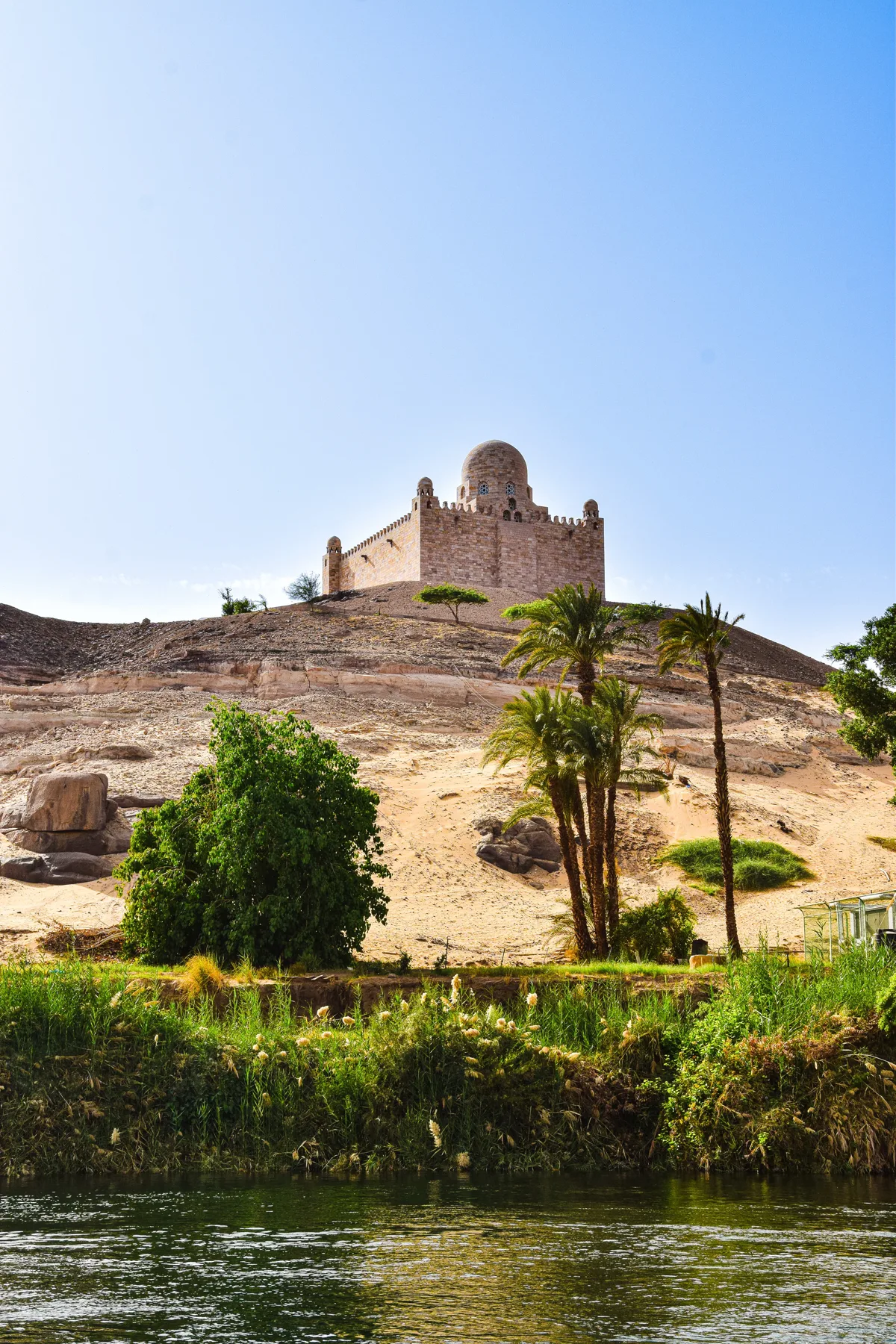 Hilltop mausoleum and palm trees beside the Nile at Aswan