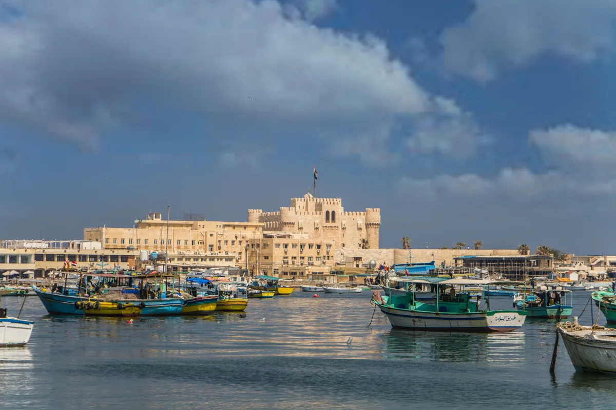 Fishing harbor and Qaitbay Citadel beneath a cloudy sky