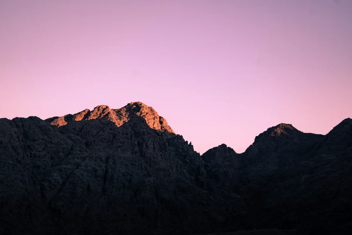 Dark Sinai mountain silhouette beneath a pink evening sky