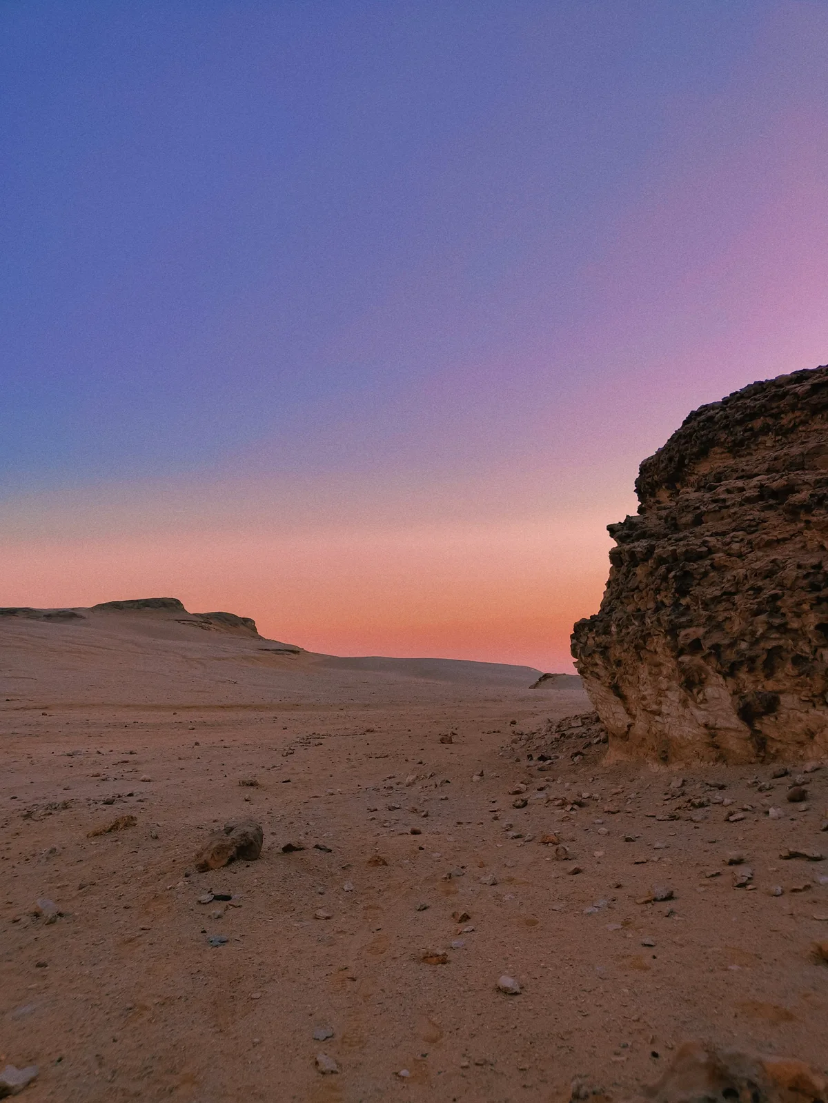 Rocky desert outcrop beneath a pink sunset sky