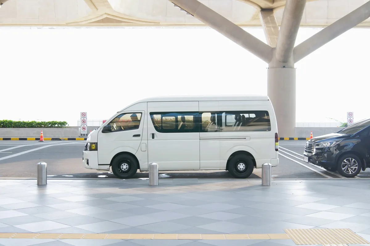 White private passenger van waiting at an airport terminal